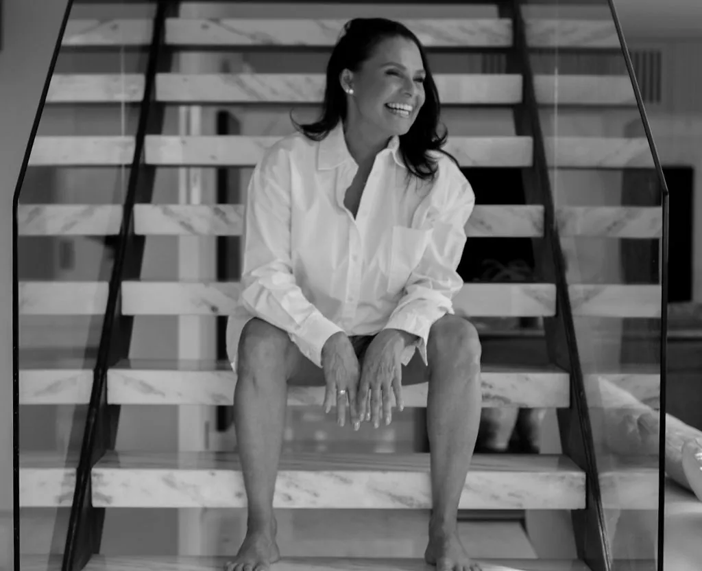 Mulher de camisa branca sentada em escada de mármore, preto e branco
